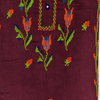 Close-up of embroidered fabric with floral patterns on a maroon background